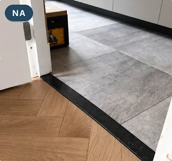 Na: een strakke natuurstenen dorpel tussen de tegelvloer en de visgraatvloer