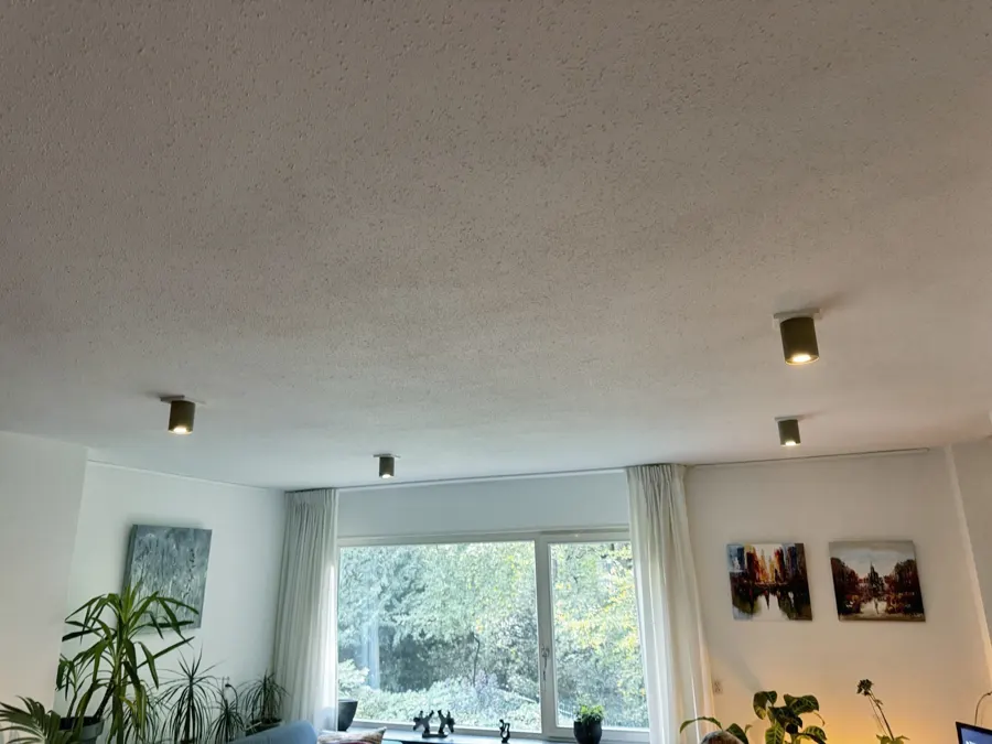 Na: de woonkamer met de nieuwe spots op witte afdekplaten